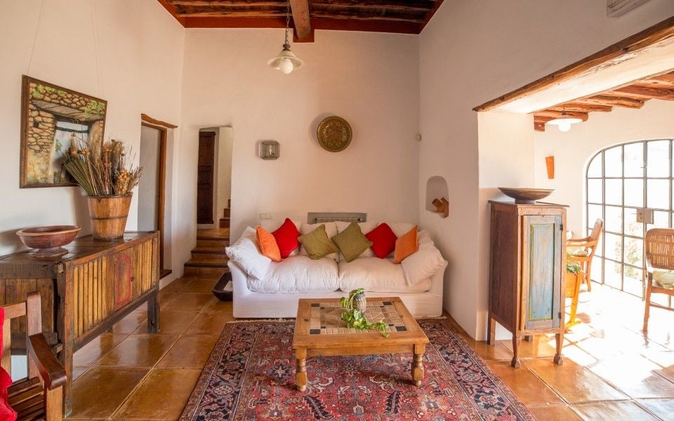 Elegant Spanish countryside hotel with stone facade, rustic wooden shutters and vibrant bougainvillea climbing its white walls