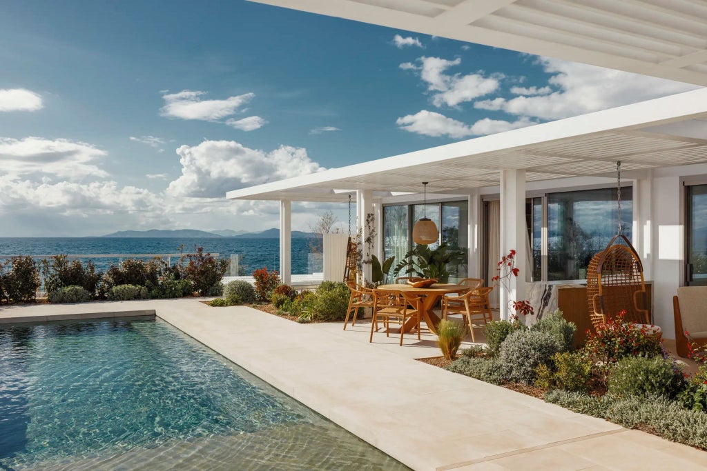 Luxurious infinity pool overlooking Aegean Sea at One&Only Aesthesis, with minimalist white architecture and panoramic coastal landscape at sunset