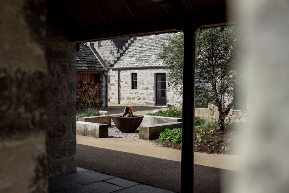 Historic Scottish stone manor with elegant grey facade, featuring large bay windows and manicured garden path leading to grand entrance.