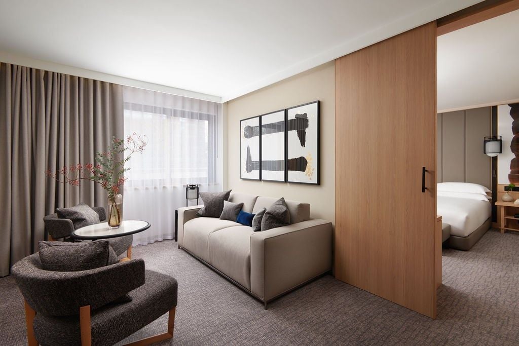 Modern, minimalist luxury hotel room with plush king bed, sleek wooden furnishings, neutral color palette, and large window overlooking urban London landscape at Nobu Hotel Portman Square