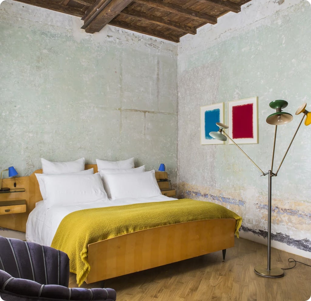 Elegant junior suite with vintage Italian design, exposed stone walls, antique furniture, and luxurious white linens in a boutique Rome hotel room