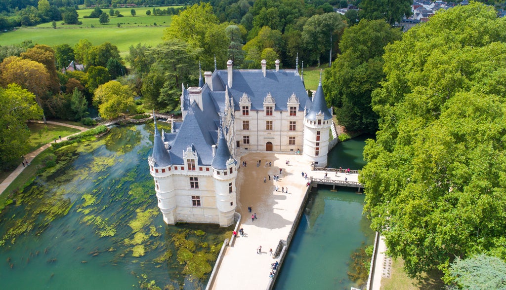 Elegant château reflected in serene Loire River at sunset, surrounded by manicured French gardens and historic stone architecture