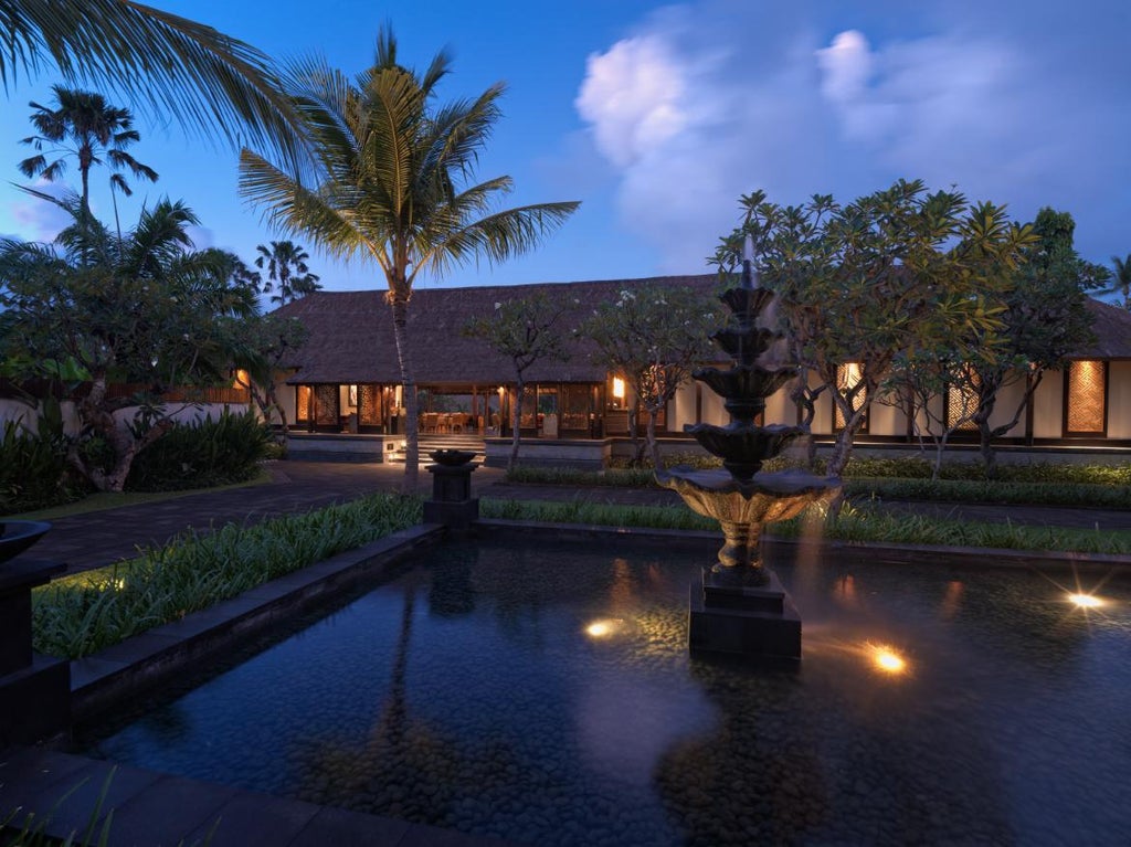 Elegant oceanfront hotel featuring multi-tier infinity pools overlooking Seminyak Beach, with manicured gardens and modern architecture