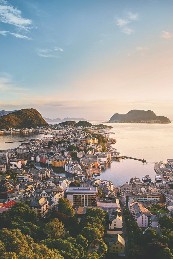 Elegant Art Nouveau buildings line cobblestone streets in Ålesund, with pastel-colored facades reflecting in harbor waters at golden hour