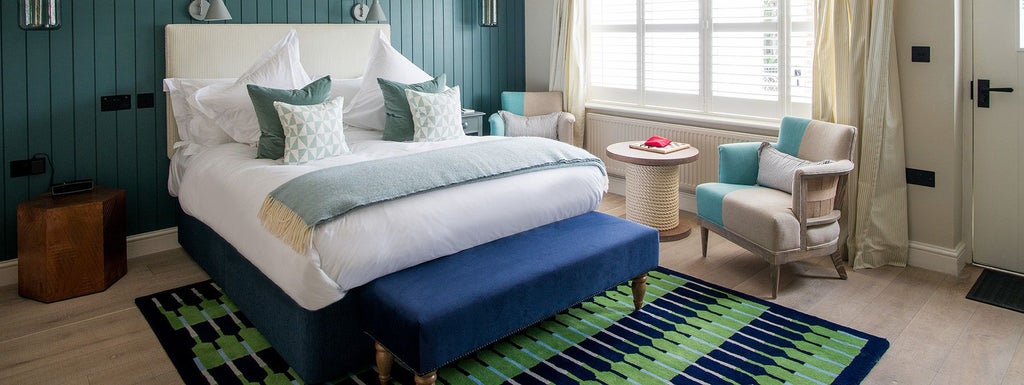 Elegant coastal hotel room at The Swan in Southwold, UK, featuring crisp white linens, nautical-inspired decor, and soft natural light through large windows