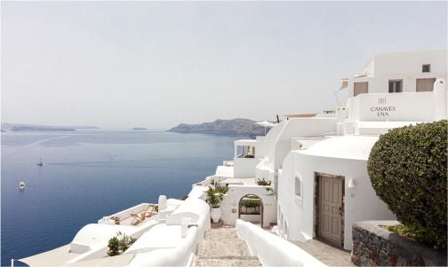 Luxurious white-washed Cycladic hotel with infinity pool overlooking azure Aegean Sea, showcasing elegant minimalist architecture in Scenset, Greece