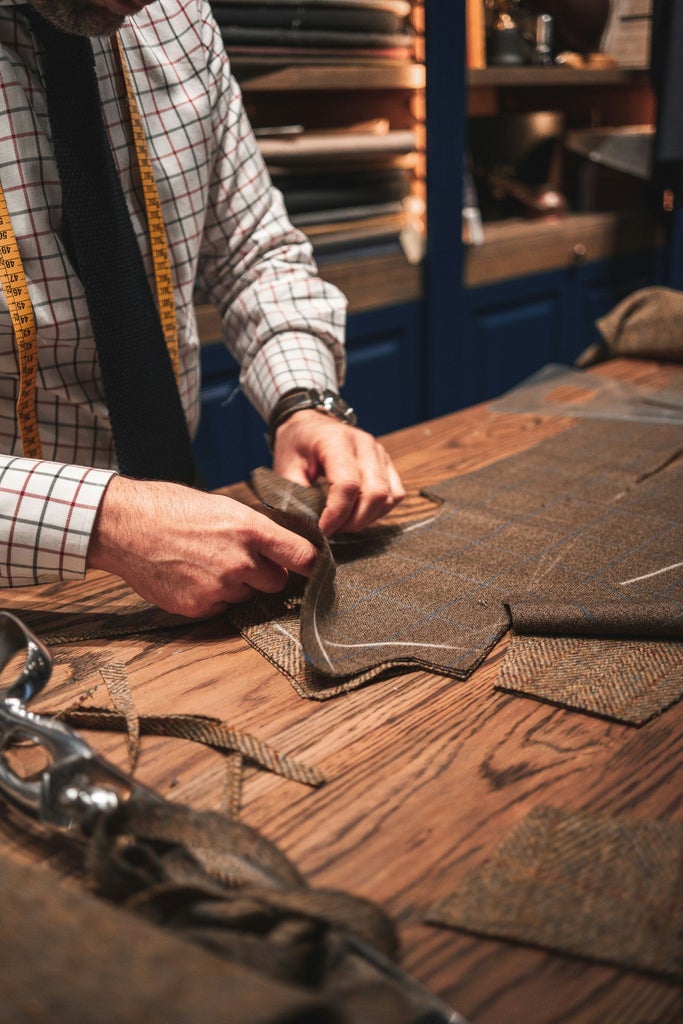 Italian artisan in traditional workshop crafting leather goods by hand, surrounded by tools and finished luxury handbags