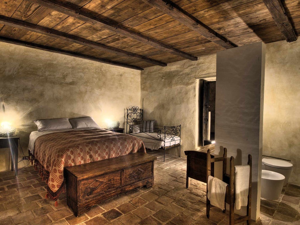 Rustic stone-walled Italian hotel room with antique wooden furniture, soft linens, and traditional stone floor in soft earthy tones