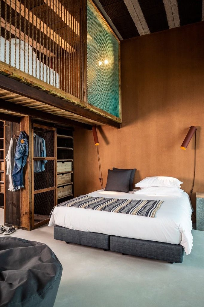 Minimalist coastal hotel room with white decor, ocean-view window, sleek wooden furniture, and soft natural lighting in Portuguese surf retreat