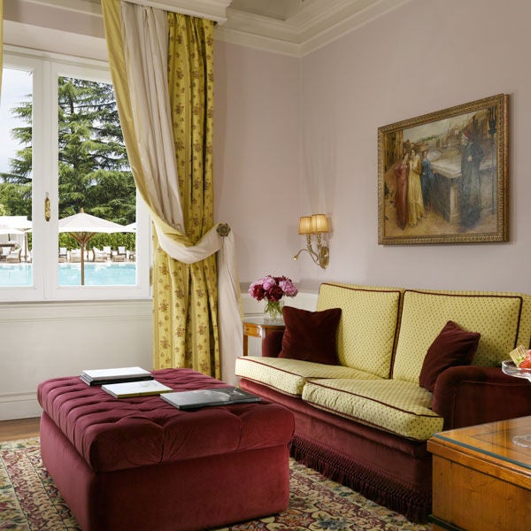 Elegant junior suite with gold-framed mirrors, ornate baroque furniture, crystal chandelier, and plush king bed draped in luxurious linens