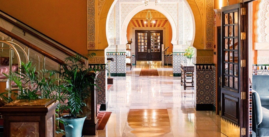 Ornate Moorish archways and columns frame a tranquil courtyard pool at the historic Alhambra palace hotel, with intricate tile work and gardens