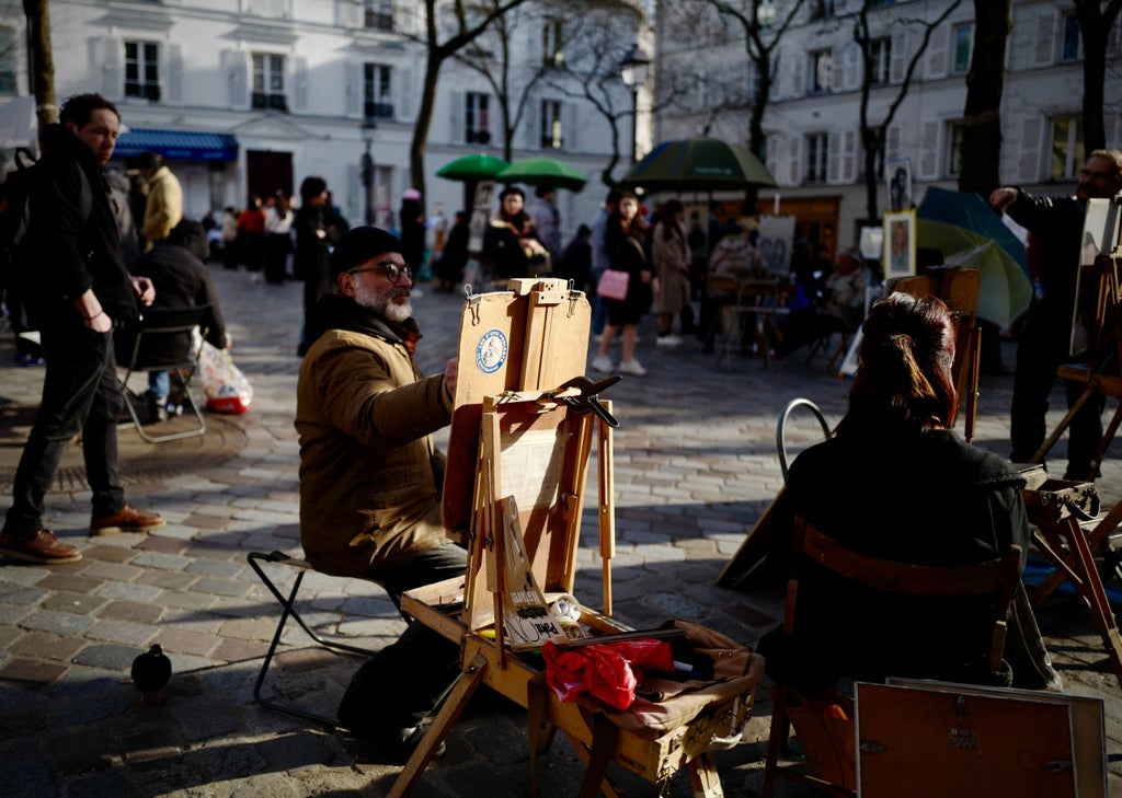 Charming cobblestone street in Montmartre, Paris, with historic white buildings, quaint cafés, and the iconic Sacré-Cœur Basilica perched on the hilltop background