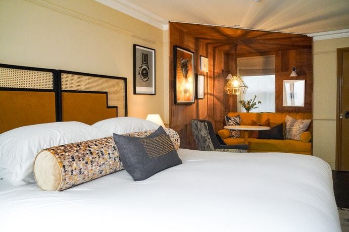 Elegant boutique suite with plush white bedding, rich wooden furnishings, vintage poetry-themed artwork, and soft ambient lighting in a luxurious United Kingdom hotel room