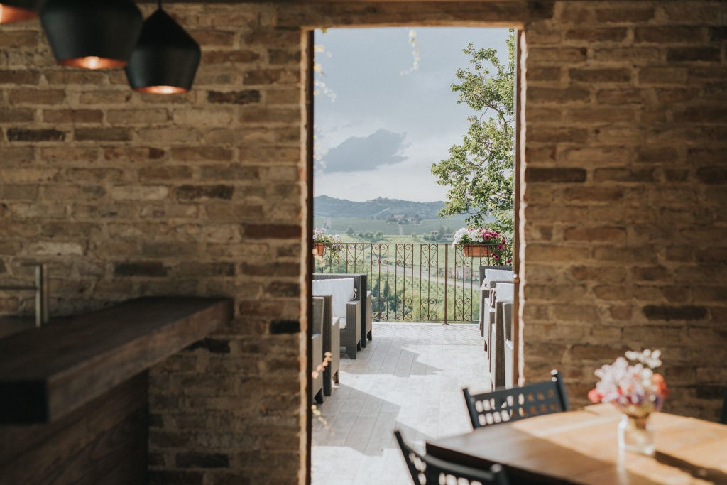 Elegant Italian luxury hotel nestled among rolling Tuscan hills, featuring stone facade, arched windows, and lush verdant gardens at golden hour