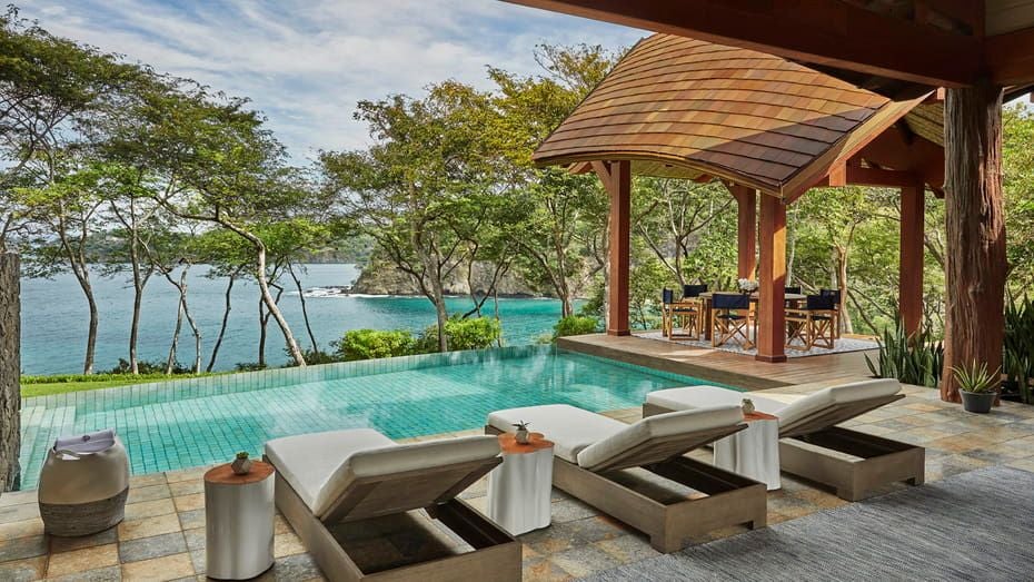 Elegant three-bedroom suite with ocean views, featuring modern furnishings, vaulted ceilings, and private terrace overlooking Costa Rica's coast