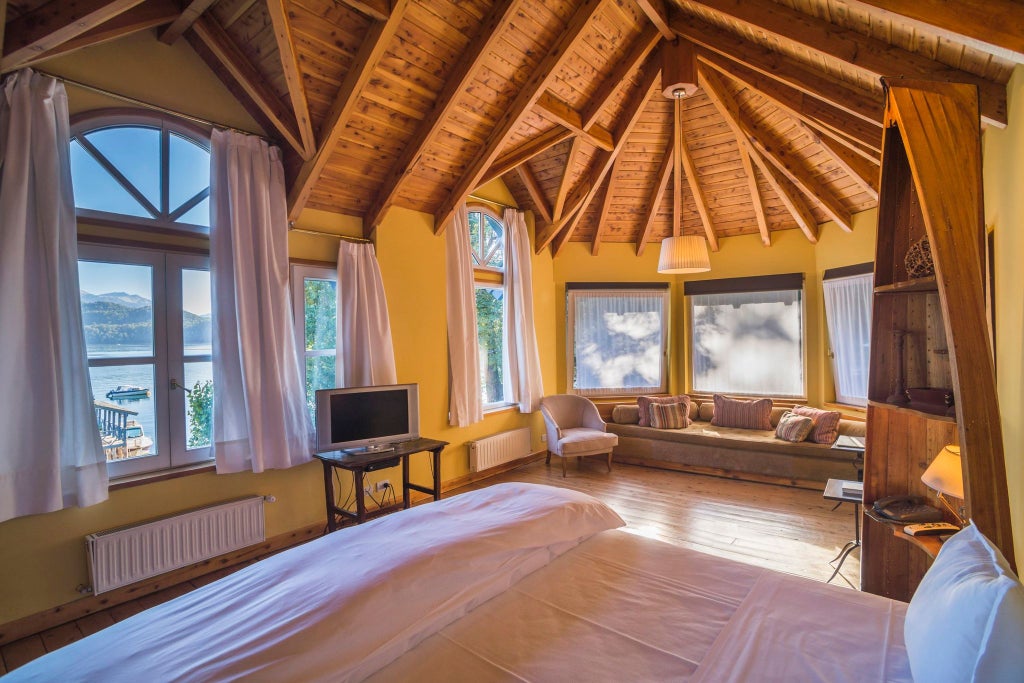 Luxurious corner suite at Las Balsas hotel, featuring elegant wood furnishings, sweeping lake views, and soft natural lighting in Patagonian wilderness