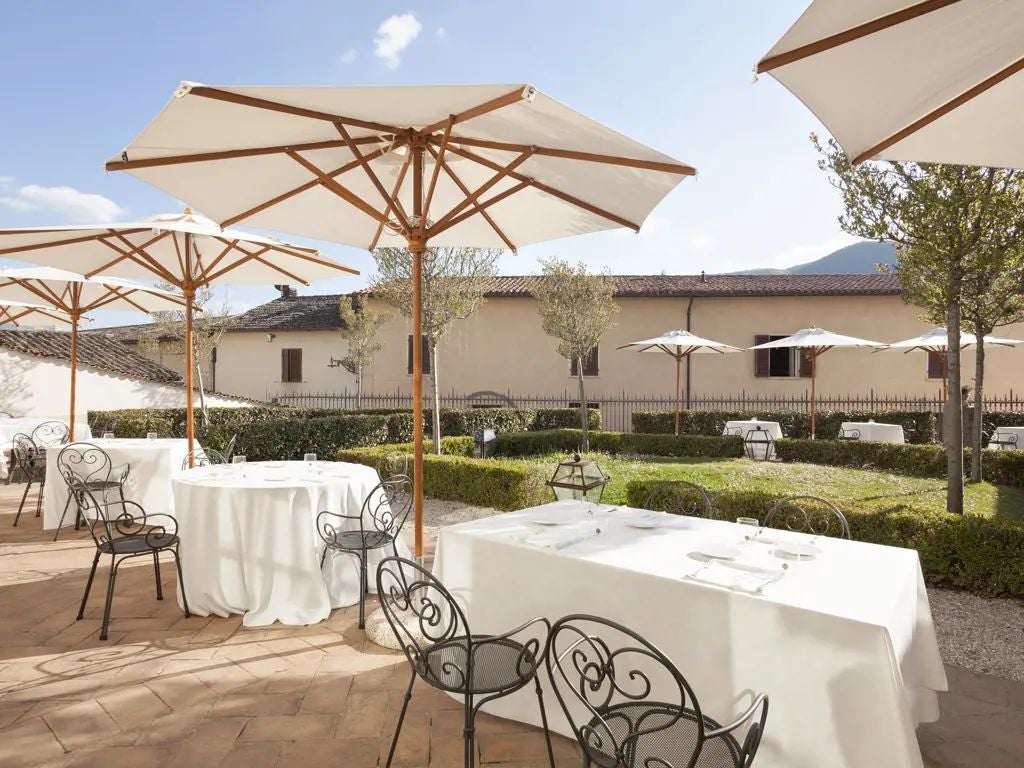 Elegant stone facade of luxury hotel nestled in historic Umbrian town, with warm terracotta rooftops and traditional Italian architectural details