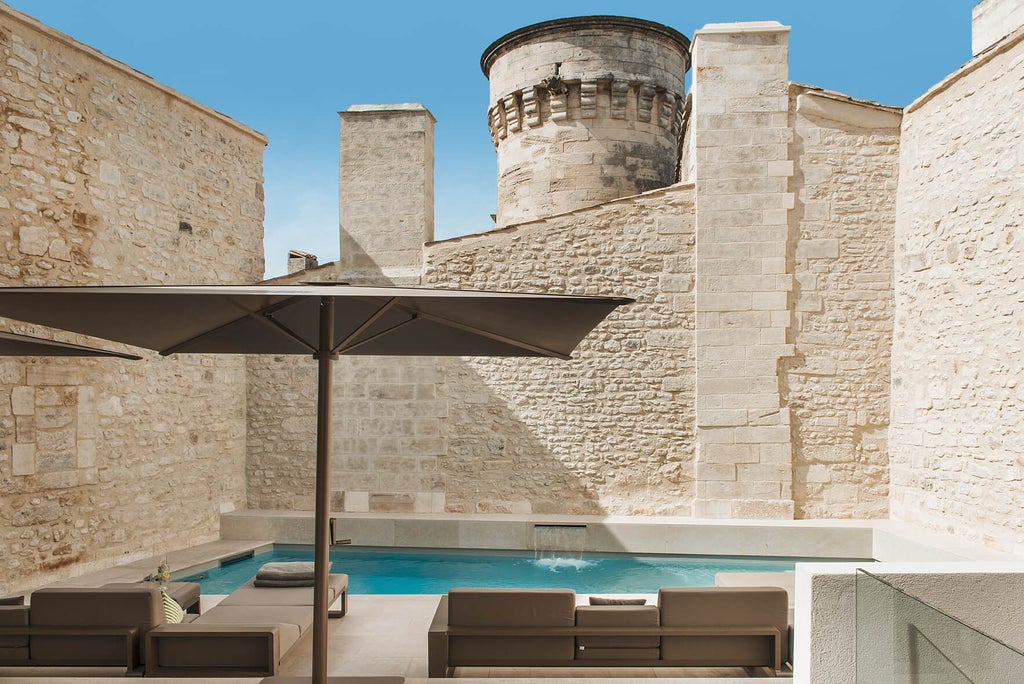 Elegant stone facade of Hotel de Tourrel with arched windows, wrought iron balconies and classic French architecture in warm sunlight