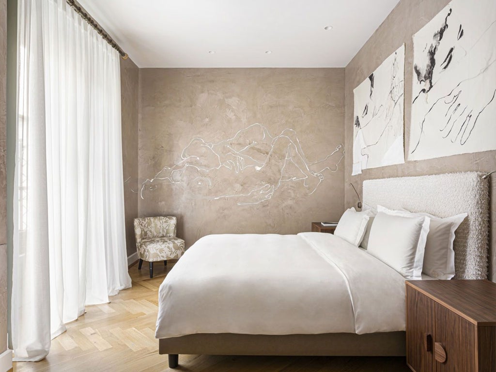 Opulent deluxe room with floor-to-ceiling windows, modern Italian design, sleek furnishings, and a stunning city view of Milano's architectural landscape.