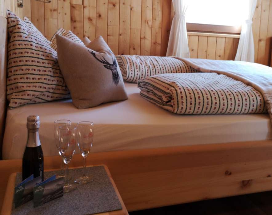 Modern twin bedroom with rustic wood paneling, panoramic mountain views through floor-to-ceiling windows, and premium bedding in earth tones