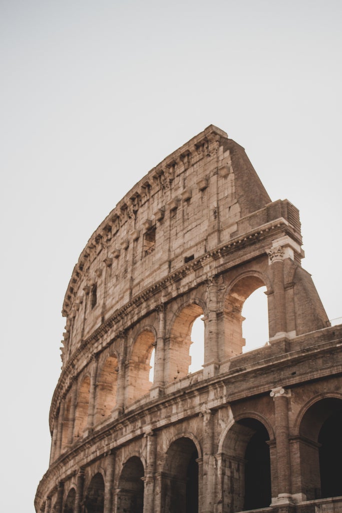 A captivating nighttime view of the illuminated Colosseum in Rome, its ancient arches glowing amber against a deep blue twilight sky