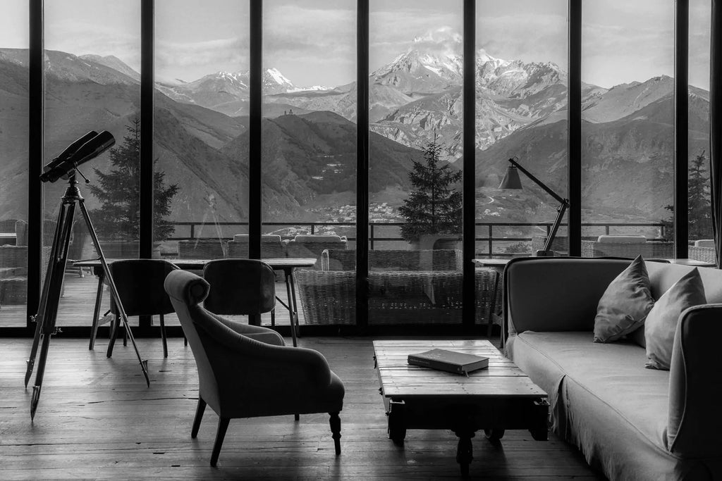 Luxurious mountain-view hotel room with modern design, large windows overlooking scenic Kazbegi landscape, featuring minimalist decor and natural wooden accents