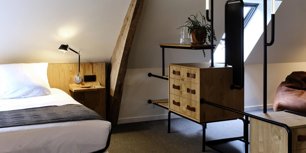 Elegant minimalist hotel room with white walls, contemporary furniture, large window, and soft natural light in French countryside château