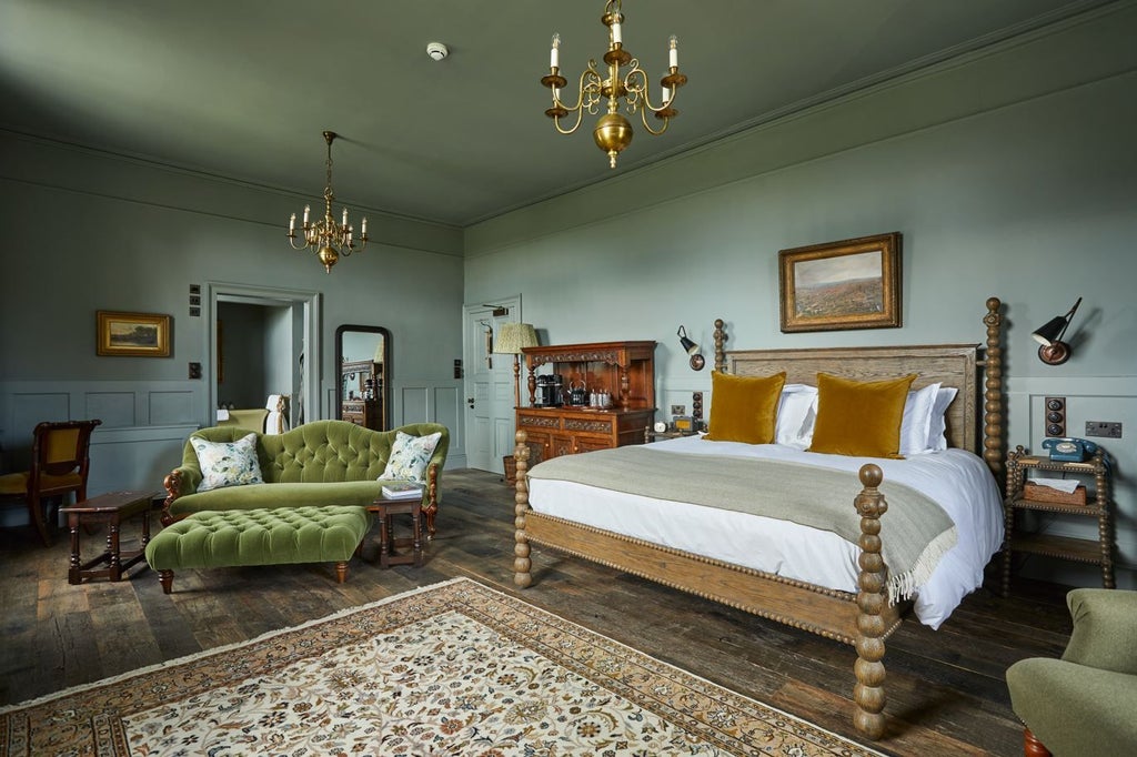 Luxurious rustic hotel room with plush king bed, vintage furnishings, and large windows overlooking lush South Downs countryside landscape