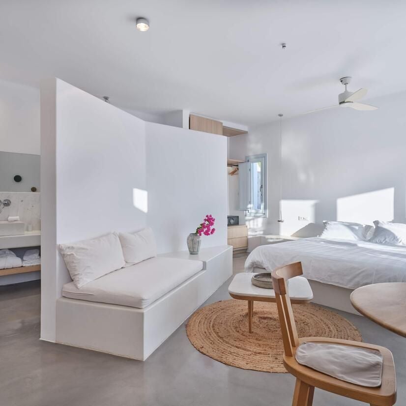 Elegant white marble suite with panoramic Aegean Sea view, lavender-infused decor, sun-drenched minimalist bedroom at luxurious Scenset Heights resort in Santorini, Greece