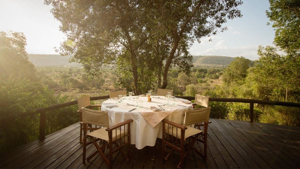 Elegant safari tent suite overlooking savanna, featuring canvas walls, private deck, rustic wooden furnishings and gauze windows at sunset