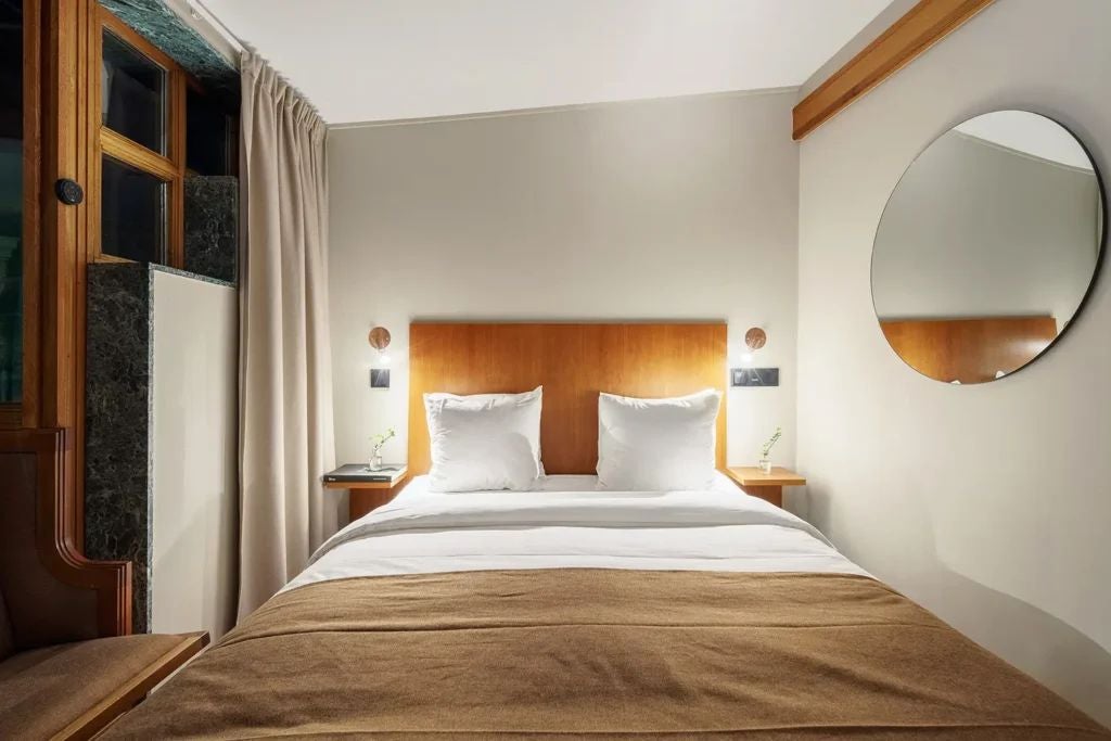 Elegant Swedish hotel room with soft neutral tones, plush king bed, modern minimalist design, warm lighting, and luxurious downtown Stockholm ambiance