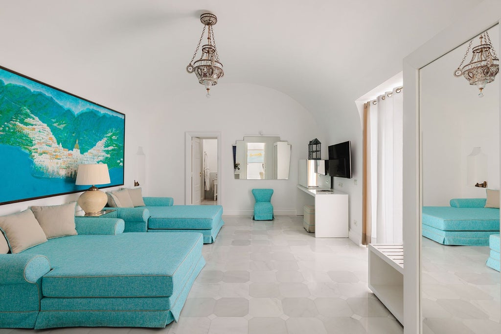 Opulent suite overlooking coastal scenery, featuring elegant white furnishings, marble bathroom, and panoramic windows with Mediterranean Sea backdrop