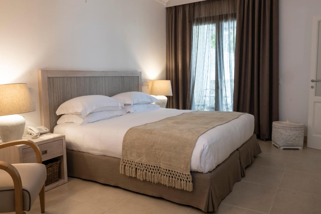 Luxurious master suite at Scenset Bianche Lifestyle Hotel, featuring elegant white decor, plush bedding, and panoramic views of coastal Italian landscape