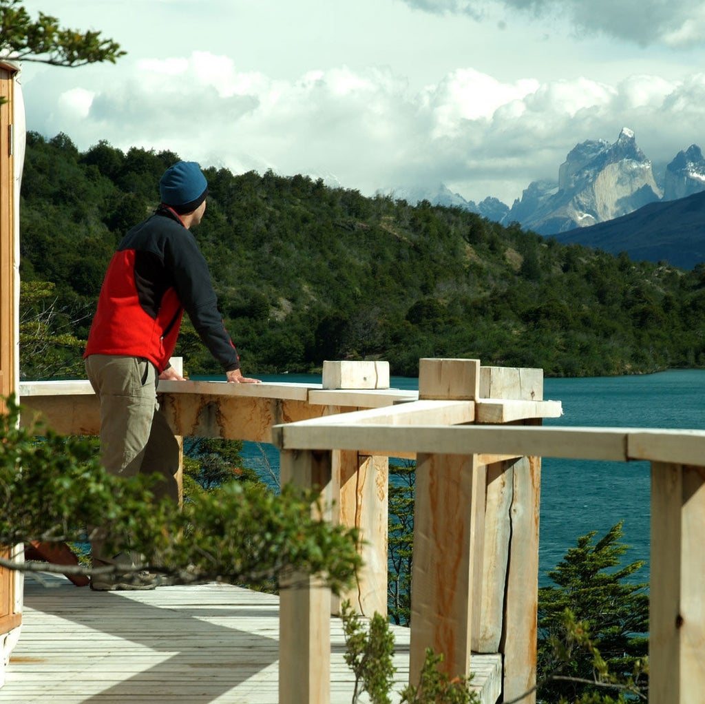 Luxury dome-shaped tent pod with panoramic windows overlooking dramatic Patagonian mountains and pristine lake at sunset