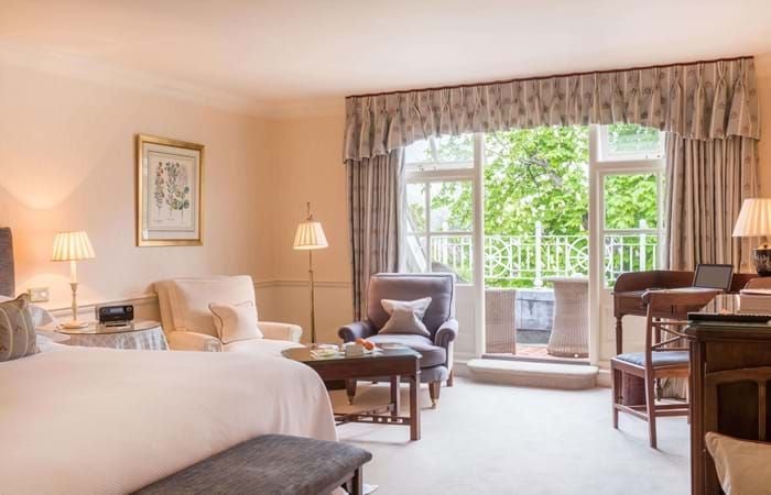 Luxurious garden room at Chewton Glen Hotel & Spa, featuring elegant furnishings, soft natural lighting, and seamless indoor-outdoor design with verdant landscape views