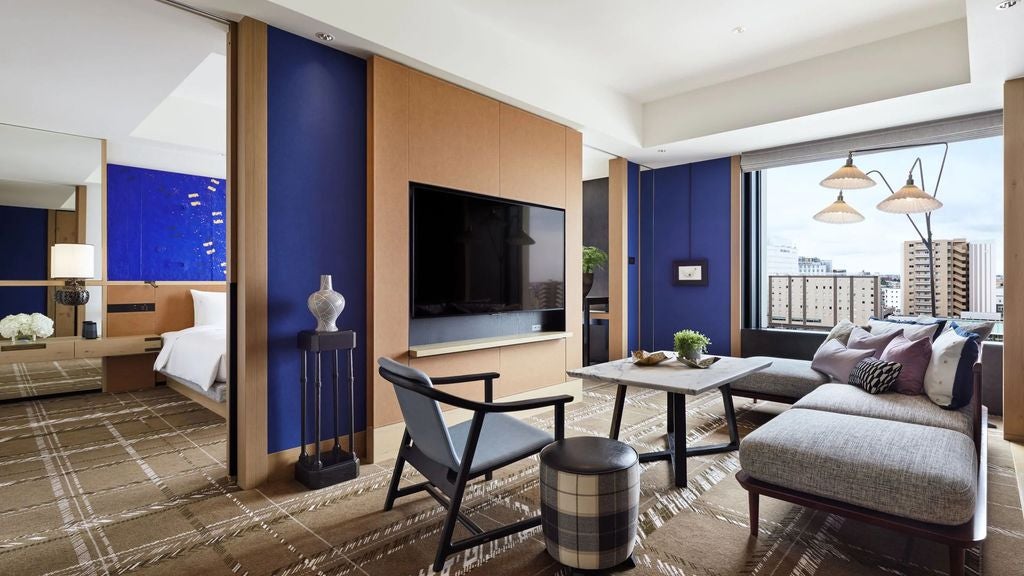 Modern king suite with floor-to-ceiling windows offering panoramic city views, sleek furniture, and muted earth-toned decor at Hyatt Kanazawa.