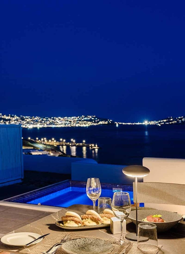 Luxurious Mykonos suite with private plunge pool overlooking azure Aegean Sea, white-washed walls, and minimalist elegant Greek island design