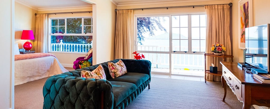 Spacious modern lodge suite with panoramic lake and mountain views, featuring elegant wooden furnishings and large floor-to-ceiling windows in New Zealand