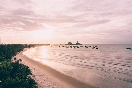 Luxurious beachfront resort with minimalist design, white architectural elements, and infinity pool overlooking turquoise waters of coastal Vietnam landscape