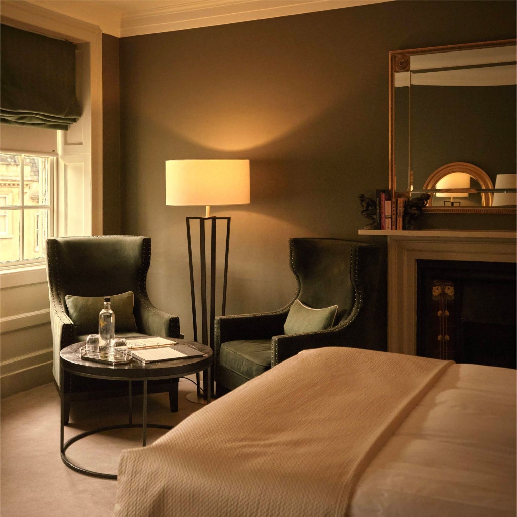 Elegant superior hotel room with cream walls, plush white bedding, classic wooden furniture, and soft ambient lighting in a UK boutique hotel setting