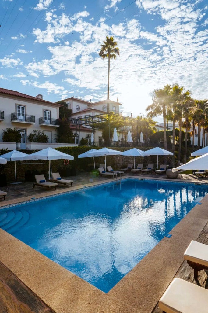 Elegant stone hotel overlooking Douro Valley vineyards, featuring historic architecture, terraced gardens and scenic riverside views