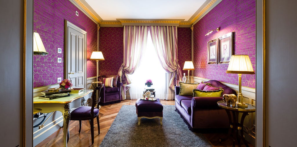 Opulent Italian hotel suite with ornate gold-framed mirrors, crystal chandeliers, and antique furniture against soft cream walls and drapes