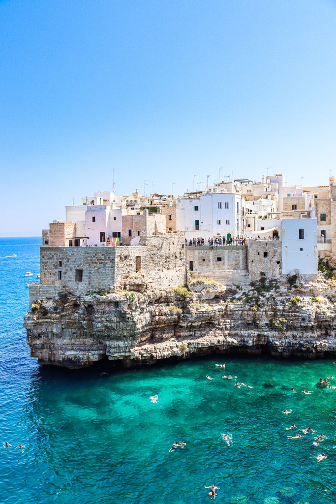 Aerial view of Polignano a Mare's iconic white limestone cliffs and traditional architecture overlooking the turquoise Adriatic Sea