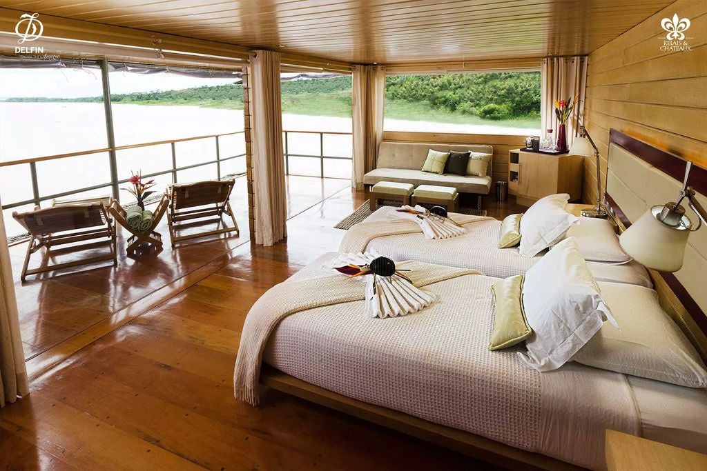 Luxurious river cruise vessel with wooden accents docked at Amazon rainforest pier, reflecting golden sunset on calm waters