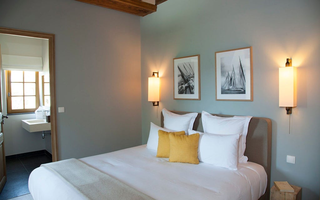 Elegant French country estate bedroom with antique white furniture, plush cream linens, soft natural light, and traditional provincial architectural details