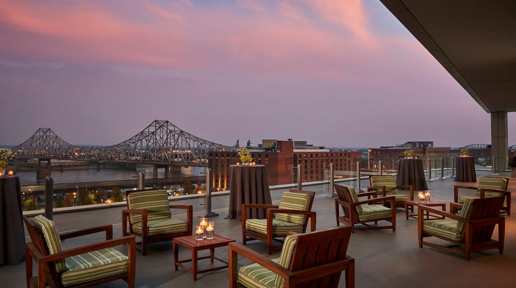 Modern high-rise Four Seasons hotel with glass façade reflecting golden sunset, overlooking St. Louis Gateway Arch and Mississippi River