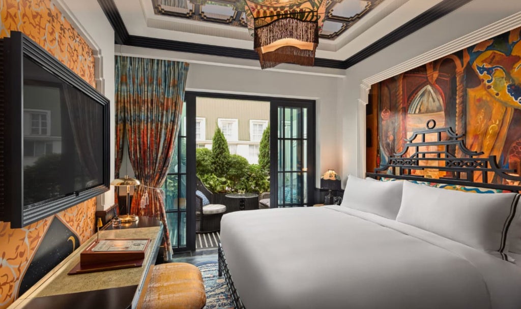 Opulent hotel suite with crystal chandelier, plush red velvet chairs, and gold-framed artworks overlooking Hanoi's Opera House.