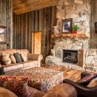 Rustic luxury lodge room with wooden furnishings, panoramic mountain views, plush bedding, and warm earth-toned decor at Scenset Mountain Ranch