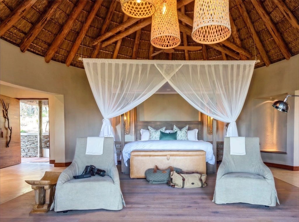 Upscale safari lodge overlooking riverbed with private plunge pool, thatched roof terrace, and expansive wooden viewing deck