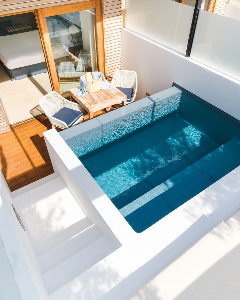 Luxurious poolside patio at Gecko Hotel & Beach Club, featuring sleek white lounge chairs, azure pool, and Mediterranean coastal vista in Spain